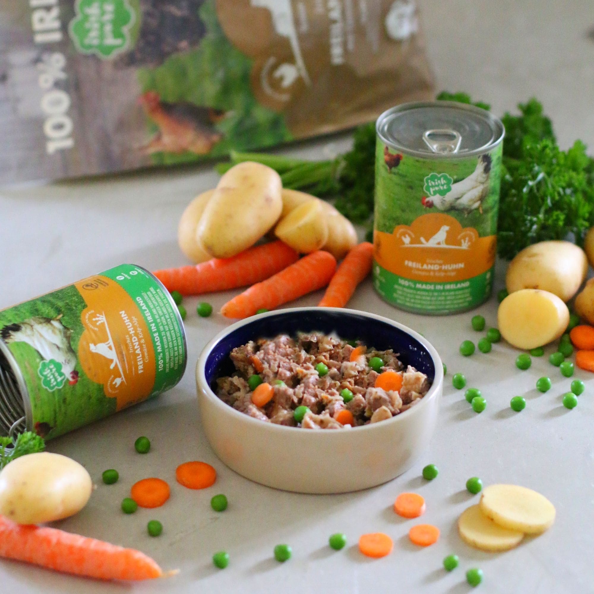 Serviervorschlag: Irish Pure Nassfutter mit Freiland-Huhn und Gemüse im Napf, umgeben von frischen Zutaten