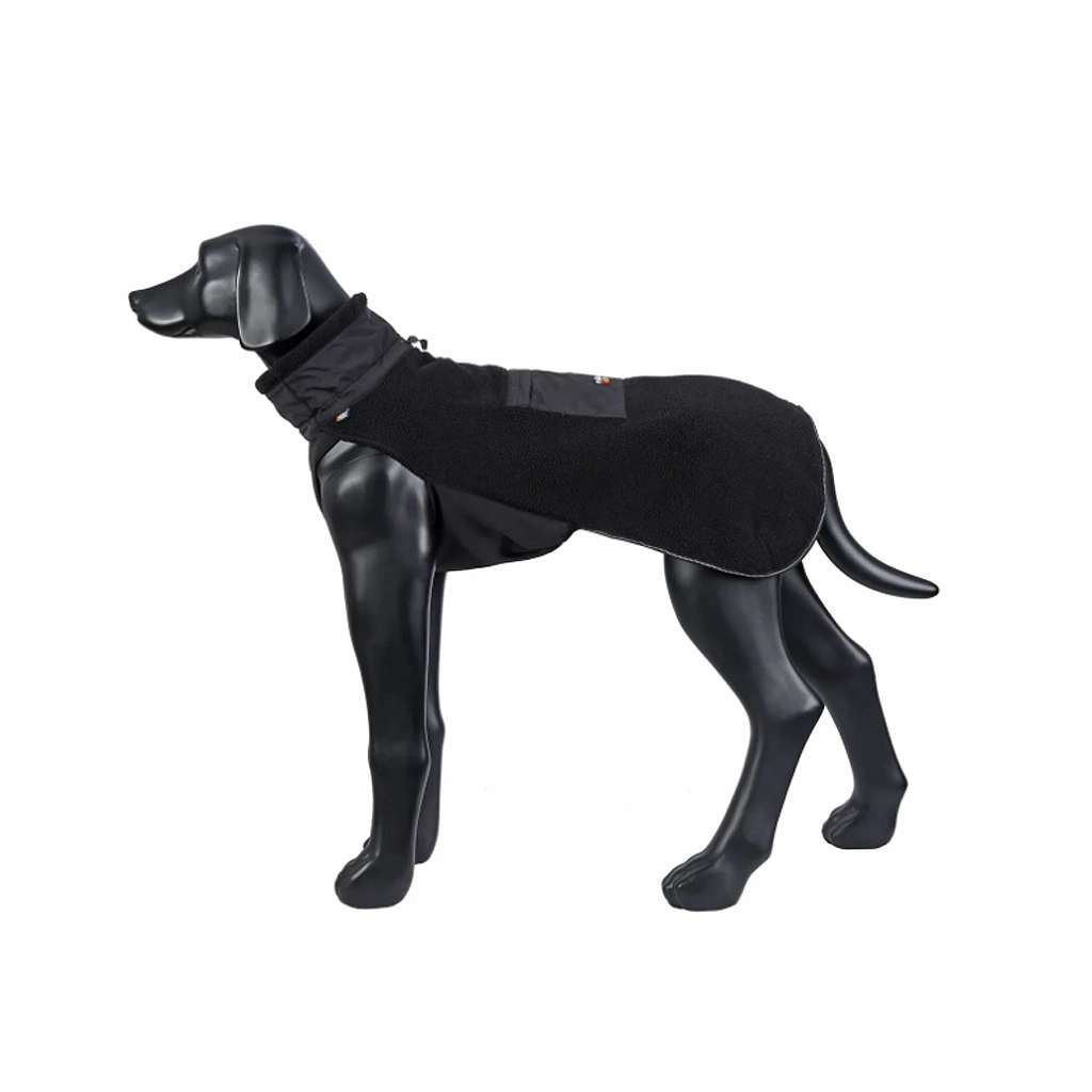 Hund steht im Profil und trägt die Rukka Pets Lucky Fleece Jacket in Schwarz, bequemer Sitz und wärmendes Material.