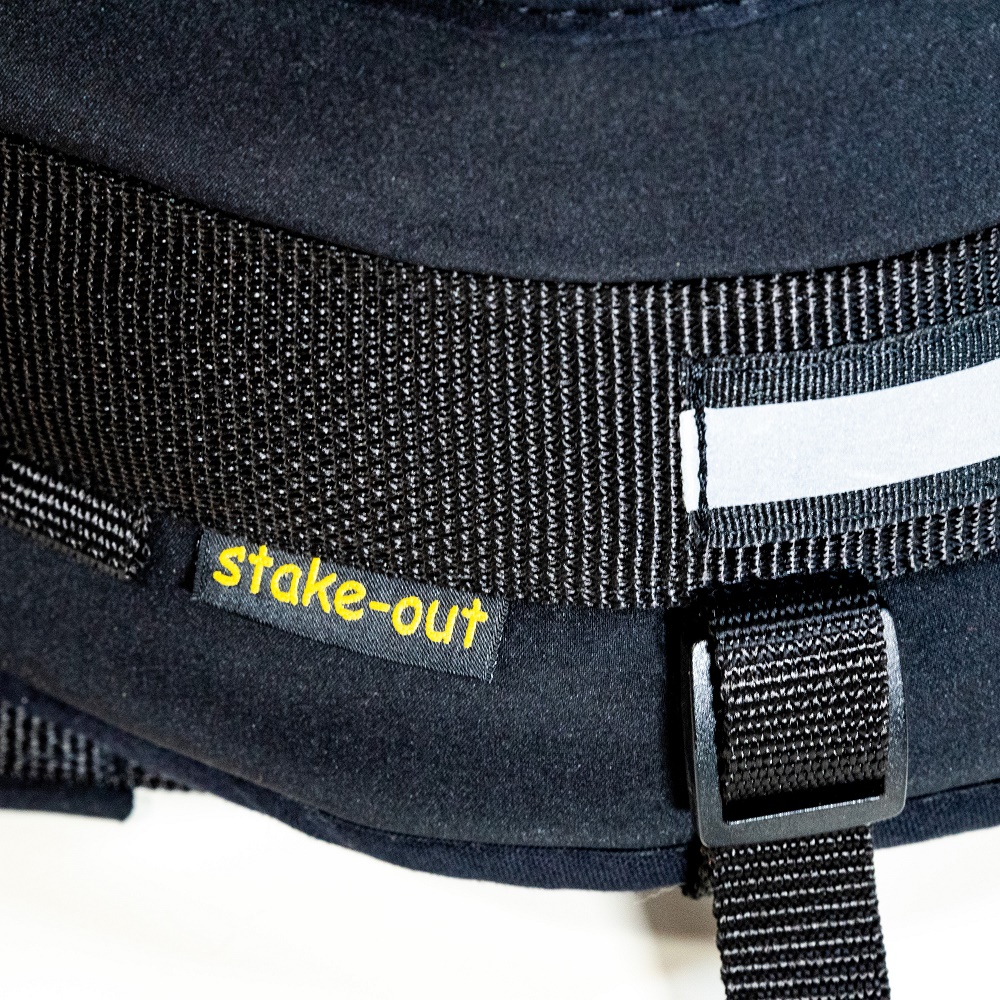 Detailaufnahme des schwarzen Zughundegürtels mit Stake-Out Label und Reflexstreifen auf weißem Hintergrund