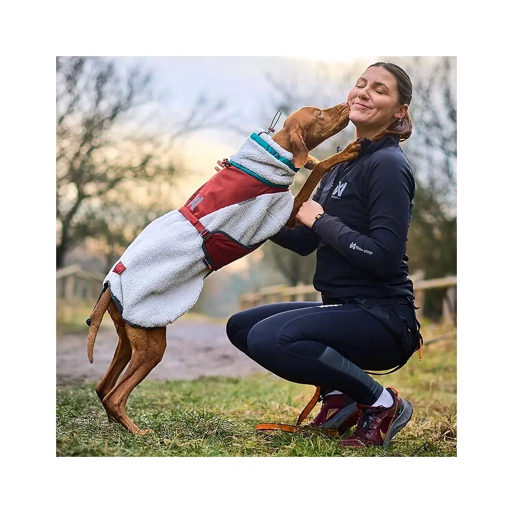 Hundebesitzer legt die Nonstop Trekking Fleece Jacke an, einfaches Anziehen durch praktische Schnallen.